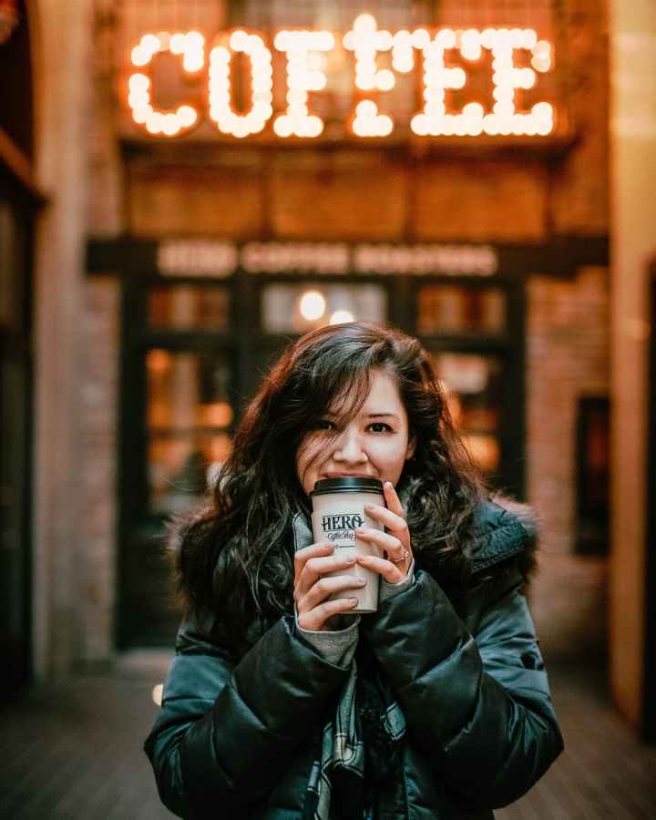 photo of woman wearing black leather jacket holding a tumbler