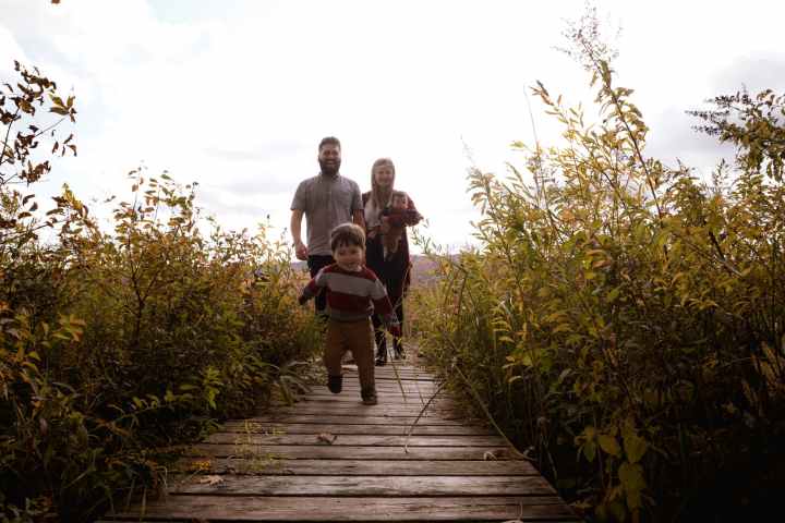 boy running on bridge near his parents