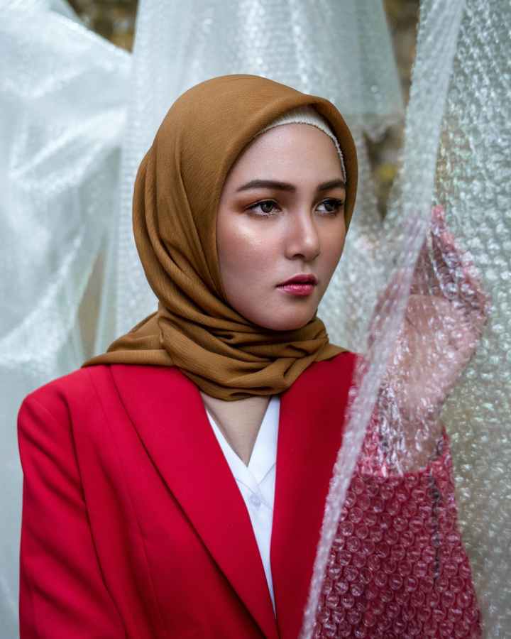 photo of woman wearing hijab while standing near bubble wrap