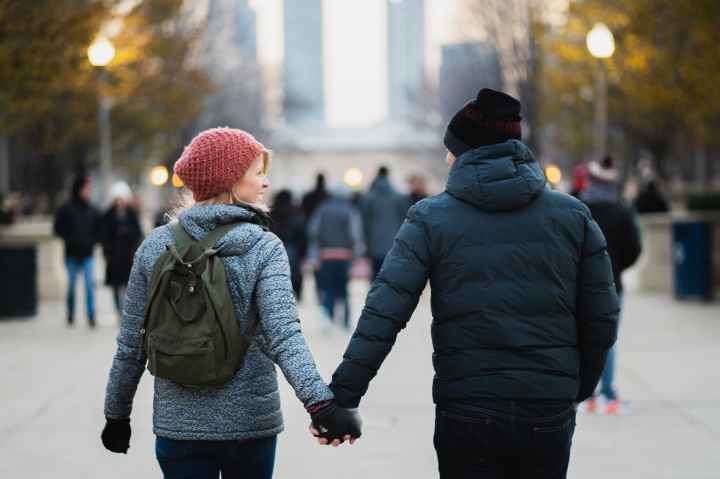 man and woman holding hands while walking at park