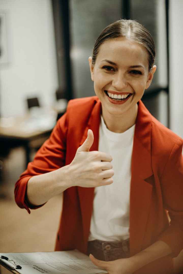 woman wearing orange blazer showing thumbs up