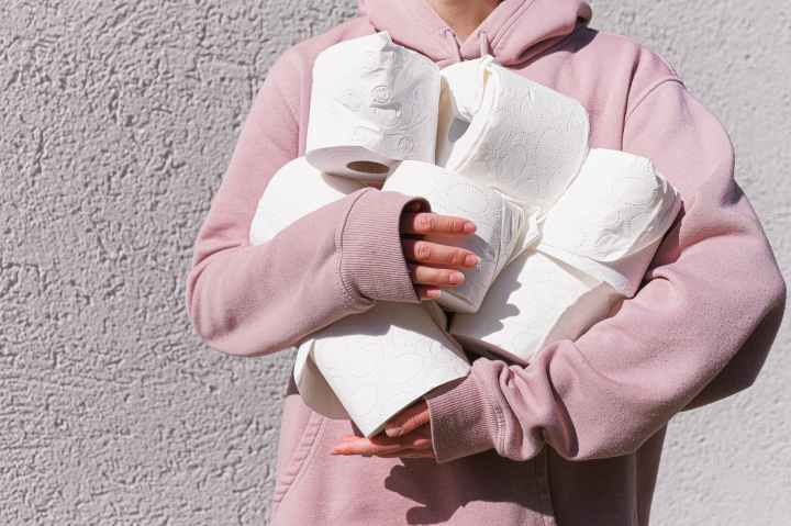 woman in pink long sleeve hoodie carrying tissue rolls