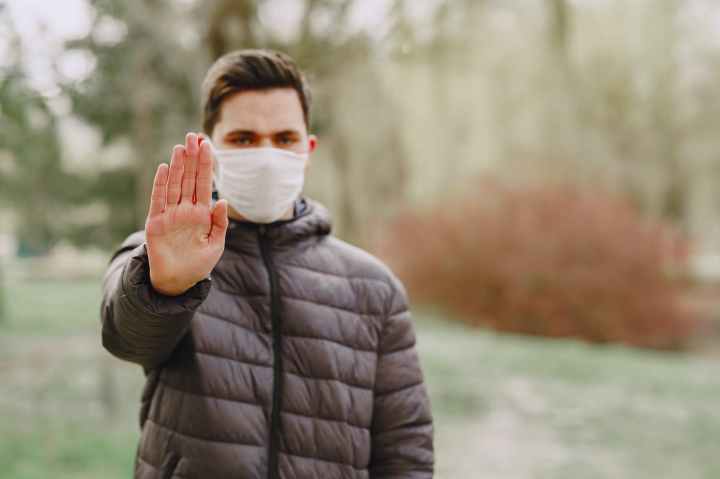man in medical mask showing stop sign